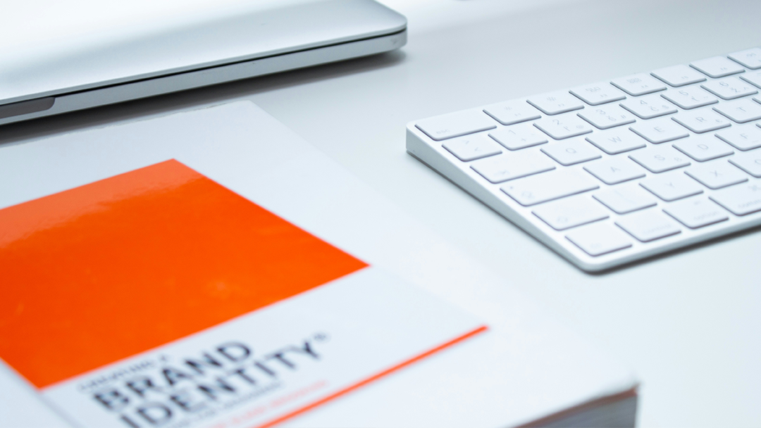 Brand guidelines document and computer keyboard on a desk.